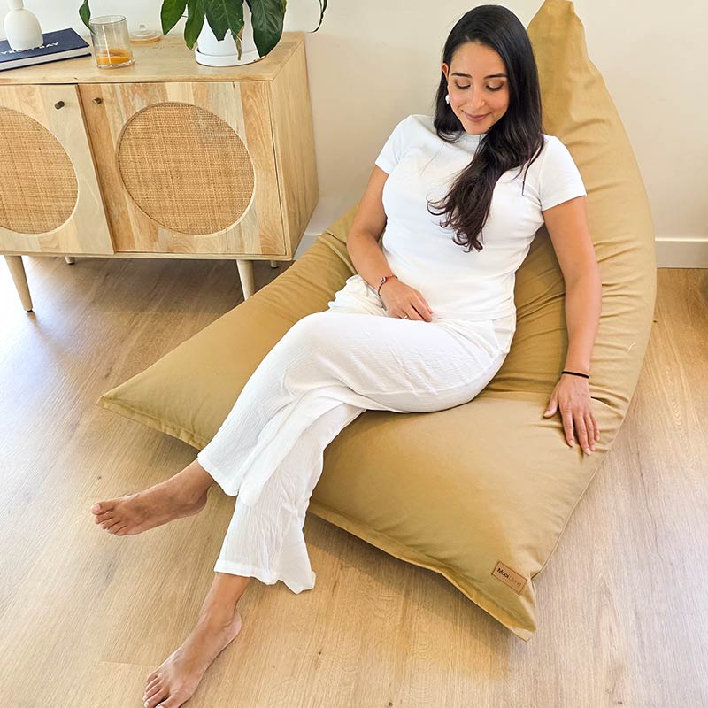 Stylish & Comfortable Tan Cotton Canvas Triangle Indoor Bean Bag Chair by Mooi Living in a warm neutral living room, woman seated.