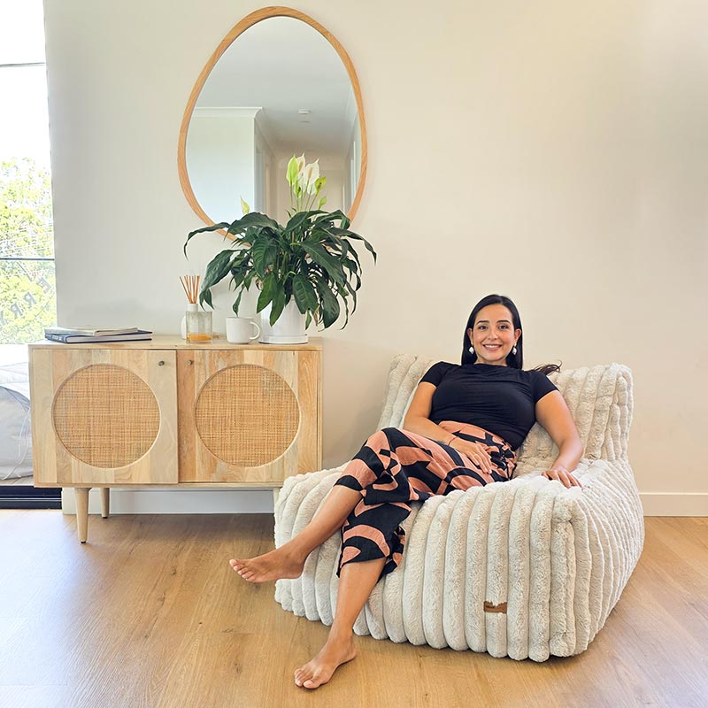 Brooklyn Luxe Lounger Foam Filled Bean Bag in Corduroy Faux Fur by Mooi Living in a light living room with timber furniture, woman seated.
