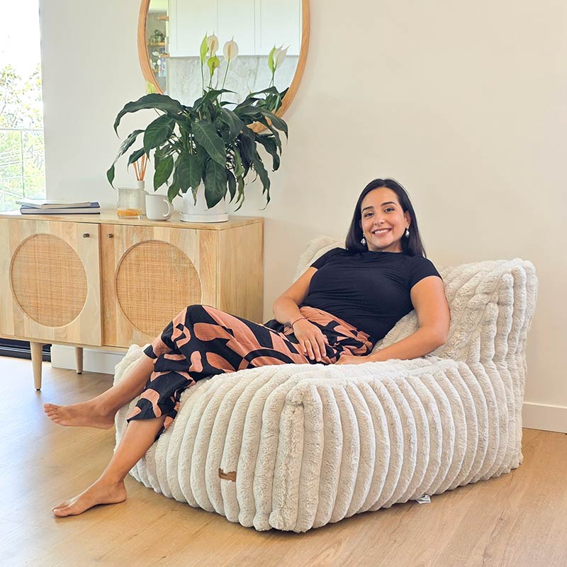 Brooklyn Luxe Lounger Foam Filled Bean Bag in Corduroy Faux Fur by Mooi Living in a light living room with timber furniture, woman seated.