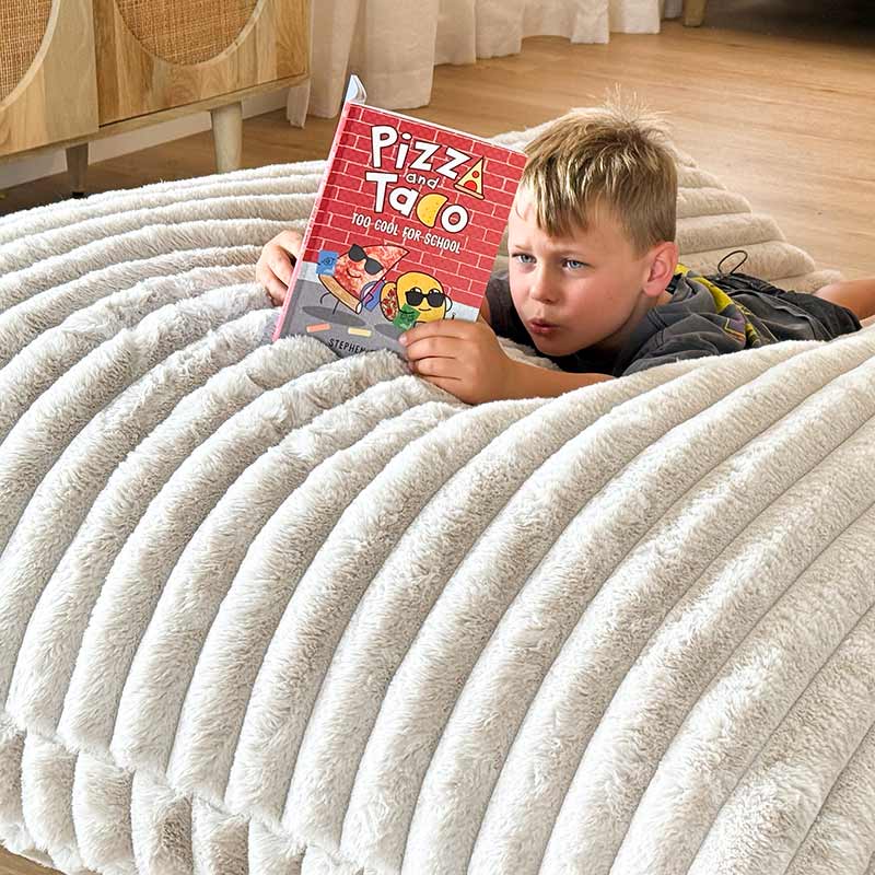 Large champagne plush bean bag mat with young boy lounging comfortably reading a book.