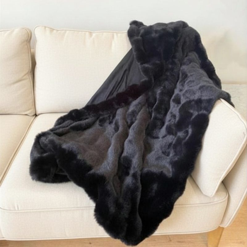 Black fur throw blanket draped over a beige sofa.