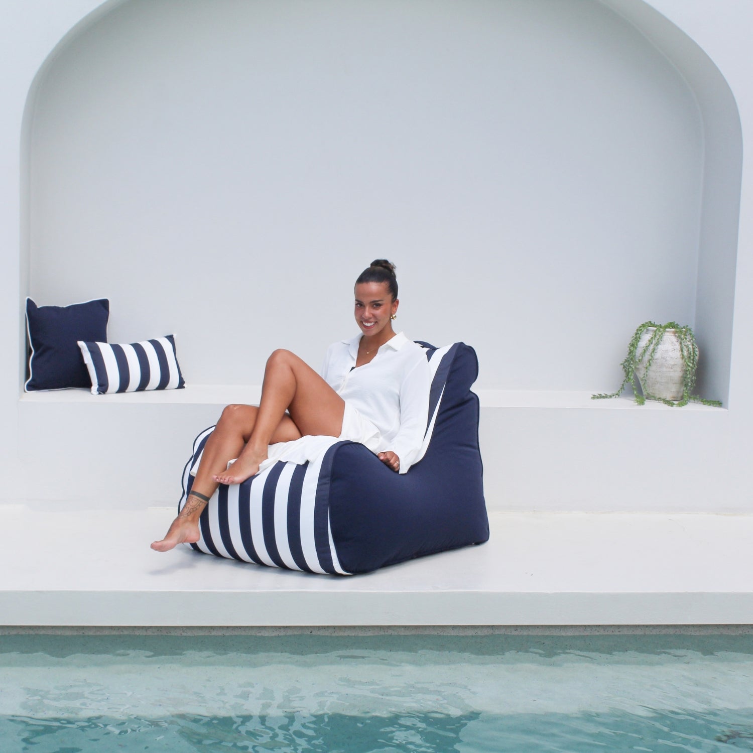 A woman sits on a navy blue and white striped Bora bean bag chair by Mooi Living, MOBORABB-STRI-NAV