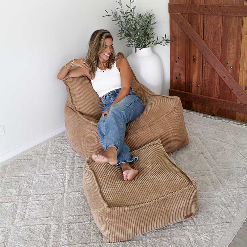 Model comfortably seats in a Mooi Corduroy Bean Bag Chair with her legs up on the matching Corduroy Ottoman.