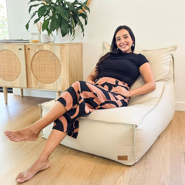 In a contemporary Australian living room, a woman sits on the Mooi Living Single Boss Bean Bag indoor bean indoor Bean Bag by Mooi Living in Natural 100% cotton canvas.