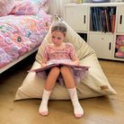 100% Cotton Canvas Mini Triangles in Natural indoor bean bag by Mooi Living with a young girl sitting and reading a book.