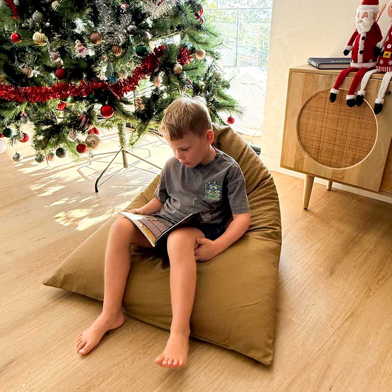 Tan 100% Cotton Canvas Mini Triangles by Mooi Living in a living room setting with a Christmas Tree, young boy seated and reading.