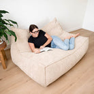 Mooi Double Seater Corduroy Bean Bag Lounger in Natural indoor bean bag by Mooi Living, woman reclining and reading in a living room.