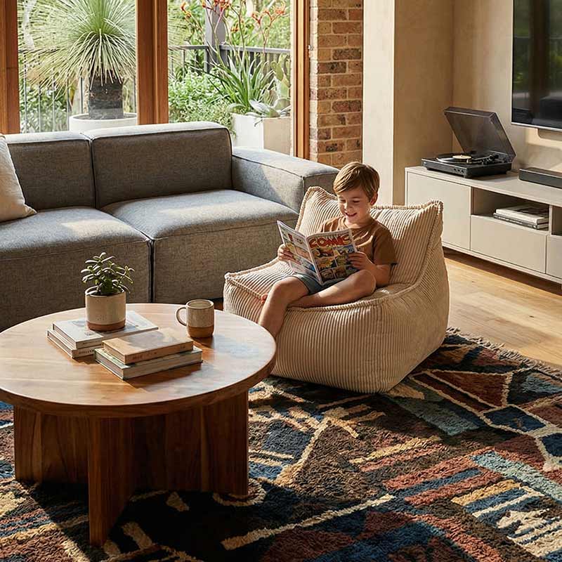 Lifestyle image of the Mini Cord Chair indoor bean bag by Mooi Living in Beige with a little boy sitting on it while reading a book in a modern living space.
