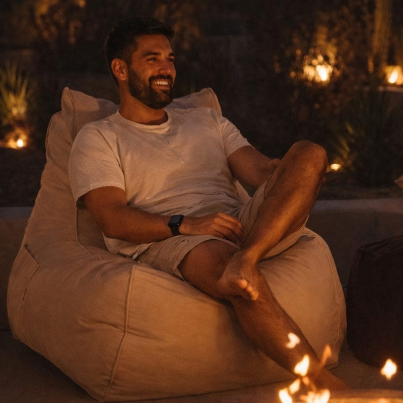 Natural Bora Bora Outdoor Bean Bag by Mooi Living at night beside a firepit, man seated outdoors.