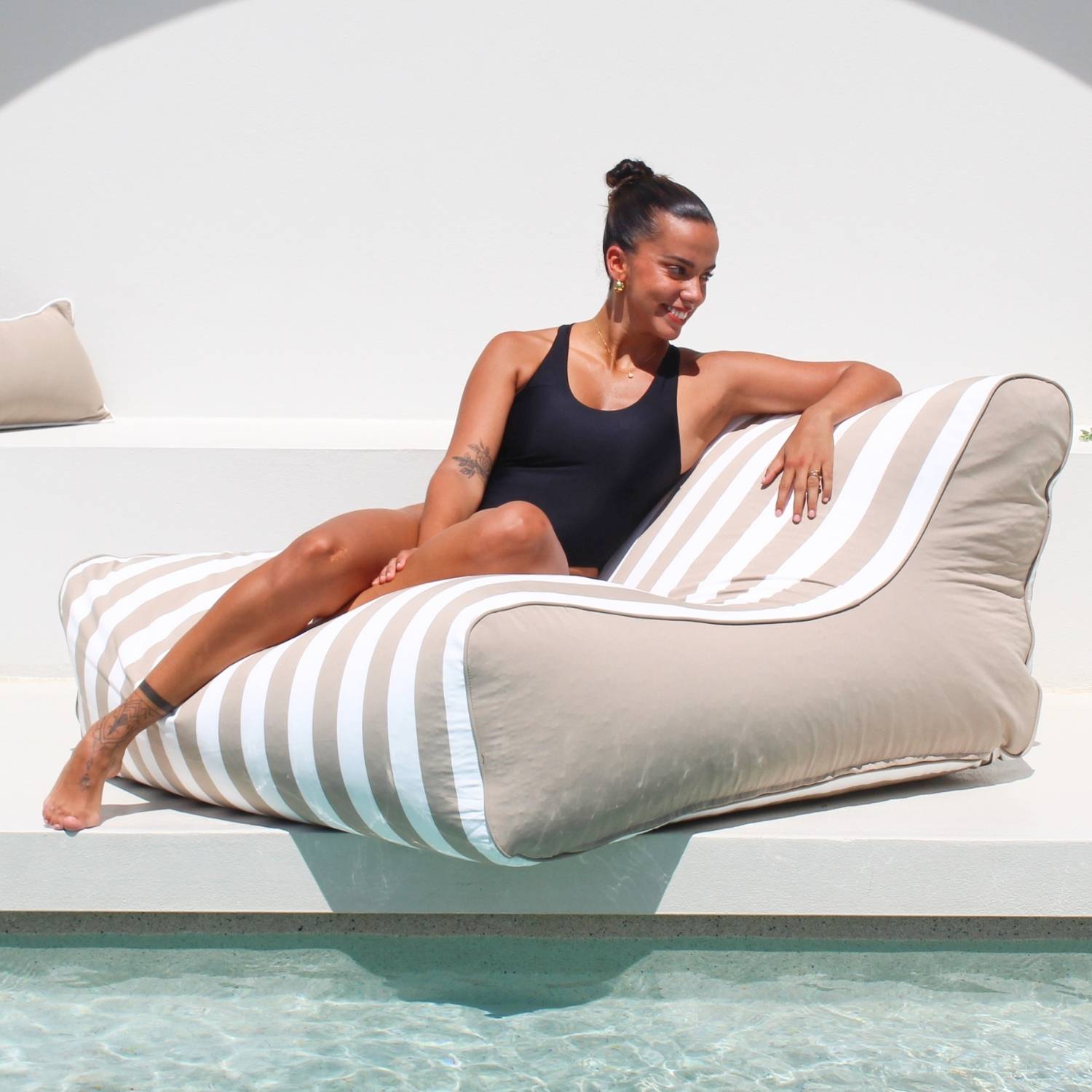 A beautiful lady relaxes poolside on a Taupe and white stripe Chill UV Lounger by Mooi Living, MOSTRCHILL-BB-TPESTR.