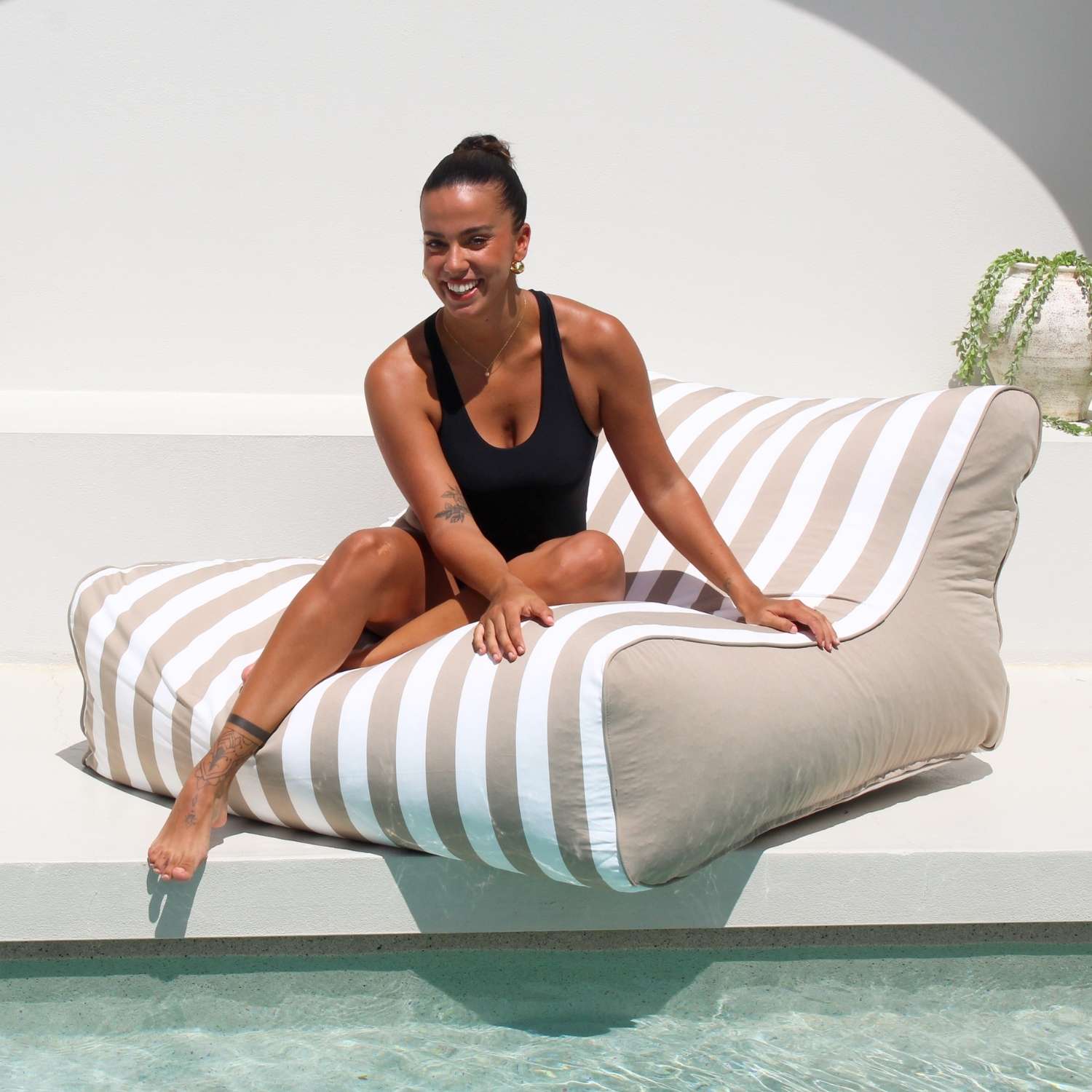 A beautiful lady relaxes poolside on a Taupe and white stripe Chill UV Lounger by Mooi Living, MOSTRCHILL-BB-TPESTR.