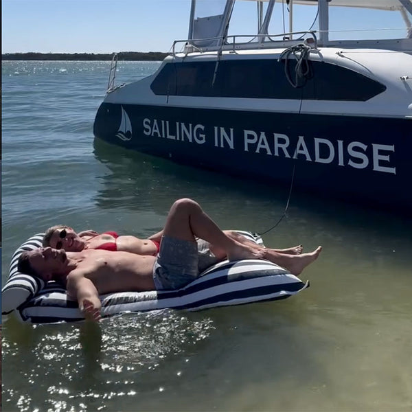 Santorini pool float beside a yacht from Sailing in Paradise Charters, luxury floating lounger in clear tropical water.
