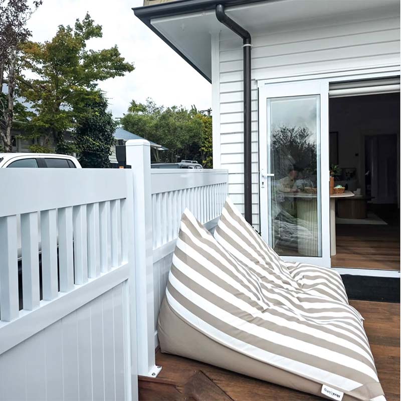 Taupe Striped Reversible Triangle outdoor bean bags by Mooi Living on a wooden deck with a white house and trees in the background 