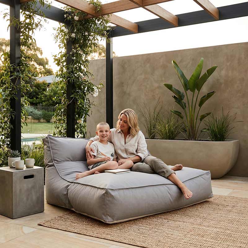Lifestyle Pic - Modern Australian patio with outdoor furniture, pergola and plants, Stone Lana double seater lounger styled in the corner of the patio, relaxed entertaining space, warm afternoon light.