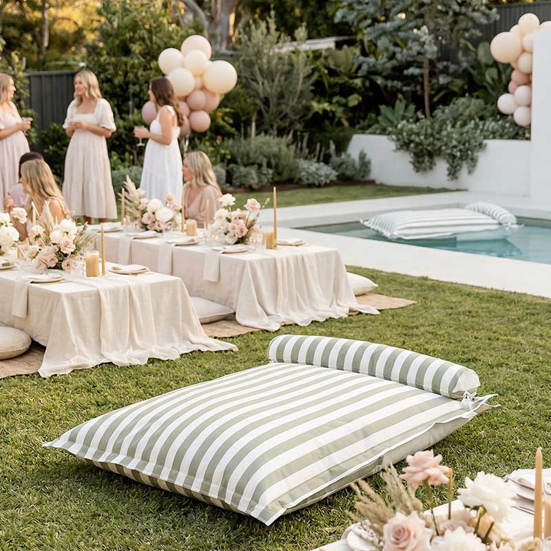 Outdoor gathering with tables set for a meal, balloons, and Santorini Floating Outdoor Bean Bag by Mooi Living by a pool.
