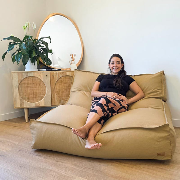 Tan Cotton Double Boss double seater bean bag chair indoor Bean Bag by Mooi Living. in a light-filled living room, a woman seated.